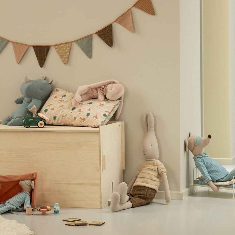Children's room with toys and a wooden shelf against a beige wall.