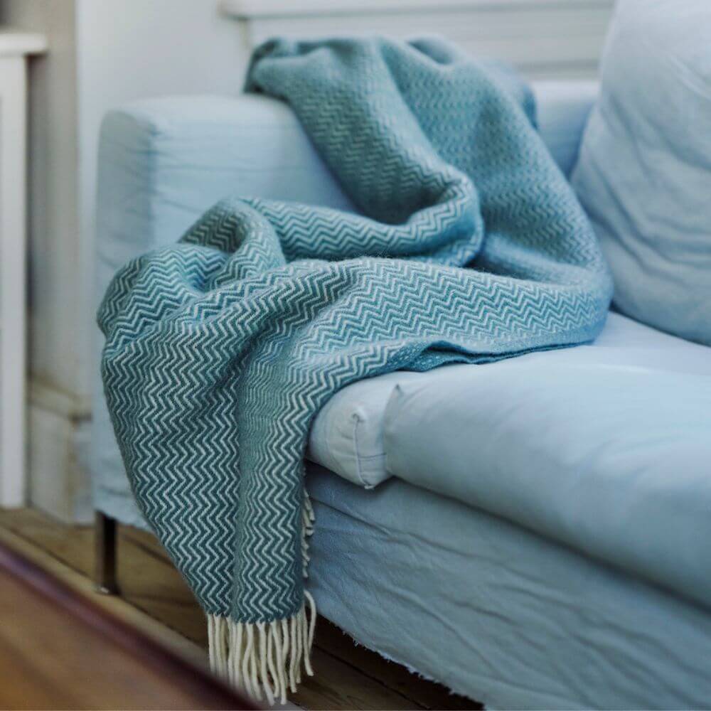 Klippan Sorbet Wool blanket draped over a light blue sofa.