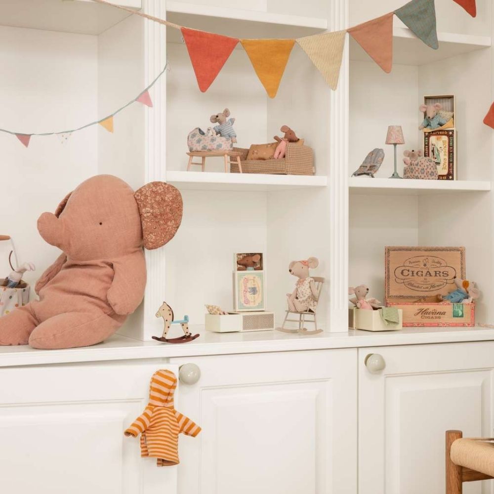 Children's room with shelves displaying toys and decorative items, featuring a large plush elephant toy.