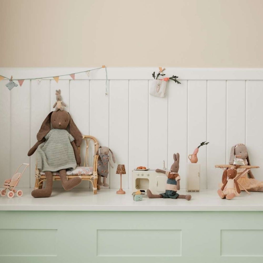 Collection of stuffed animals in a child's playroom setting with a white wall and green baseboard.